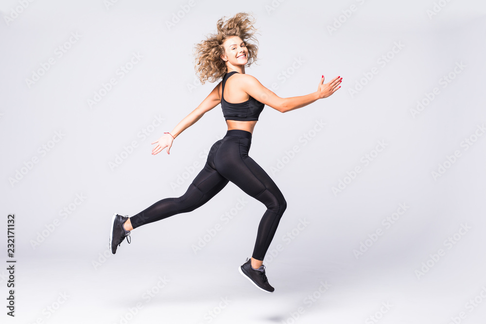 Full length picture of fitness woman jumping over gray background
