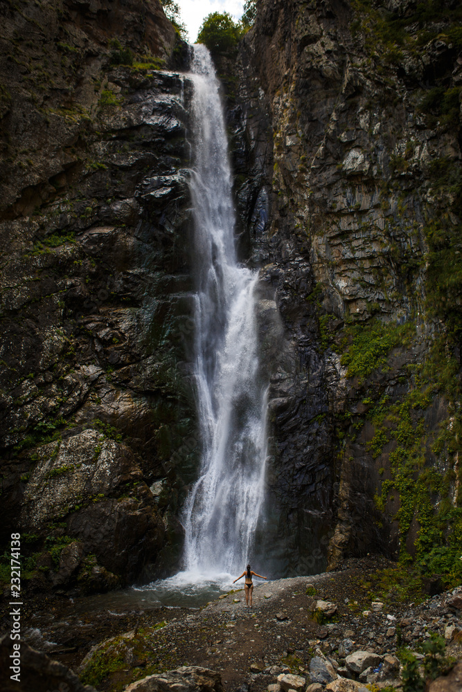 A high waterfall with white splashes of water descends from the mountain and sparkles in the sun. Attraction of Georgia Gveleti waterfall A high waterfall with white splashes of water descends from the mountain and sparkles in the sun. Attraction of Georgia Gveleti waterfall