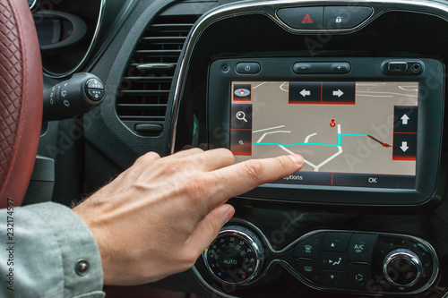 male hand indicates the destination point on the navigator in the car