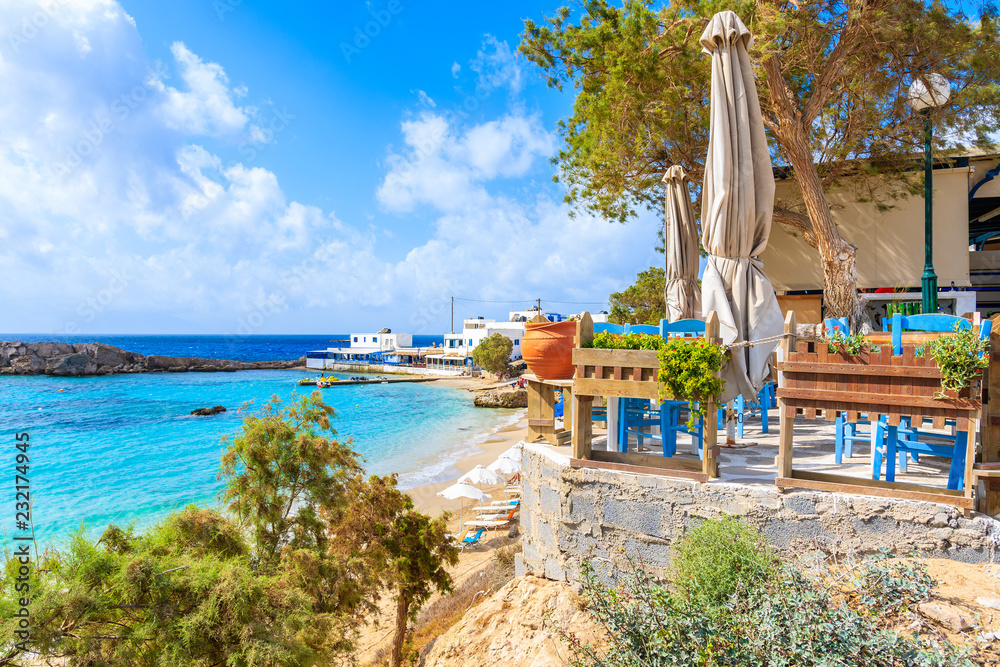 Taverna terrace on beautiful beach in Lefkos village on coast of Karpathos island, Greece - obrazy, fototapety, plakaty 