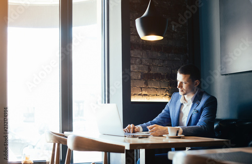 Young man drawing template for the web site associated with digital marketing, current trends and tendencies of UX / UI design. Businessman who rules his company remotely, like a freelancer