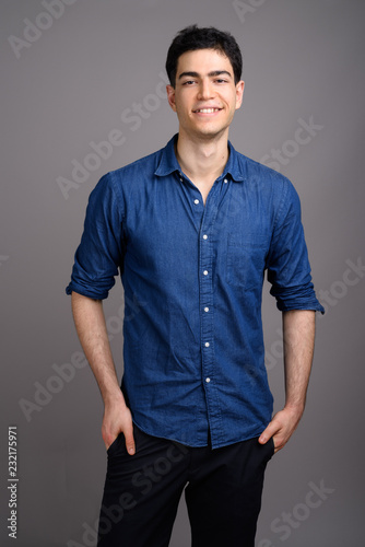 Portrait of young handsome businessman against gray background © Ranta Images