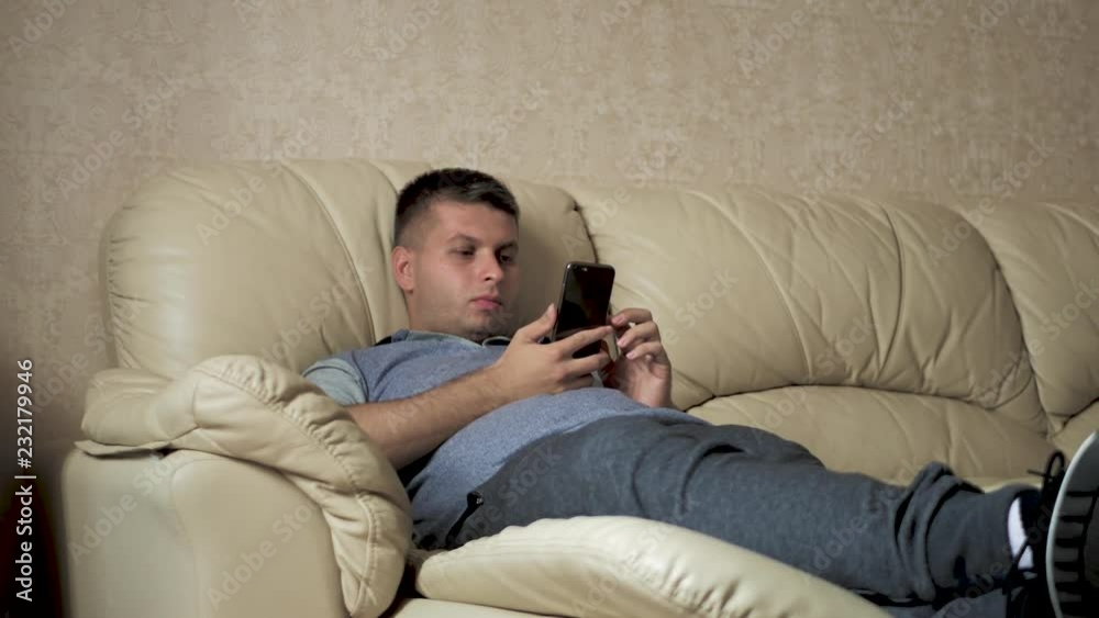 Man using a mobile phone at home on the sofa. Man using a mobile phone at home on the sofa.