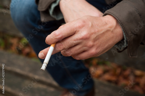 closeup of man with cigarette in hand in outdoor
