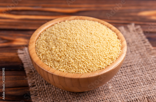 Raw couscous grain in wooden bowl with burlap napkin