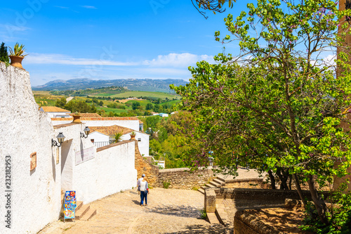 RONDA, SPAIN - MAY 10, 2018: Couple of people walking down the street in Ronda village, Andalusia, Spain. This place is famous tourist destination.