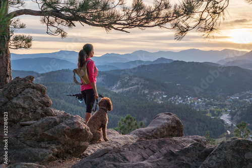 A hispanic woman is hiking with a dog, at sunset, in the Rocky Mountains near Denver, Colorado, USA photo