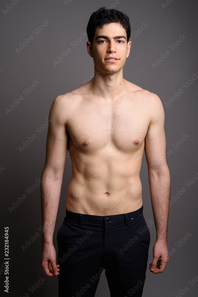 Young handsome man shirtless against gray background