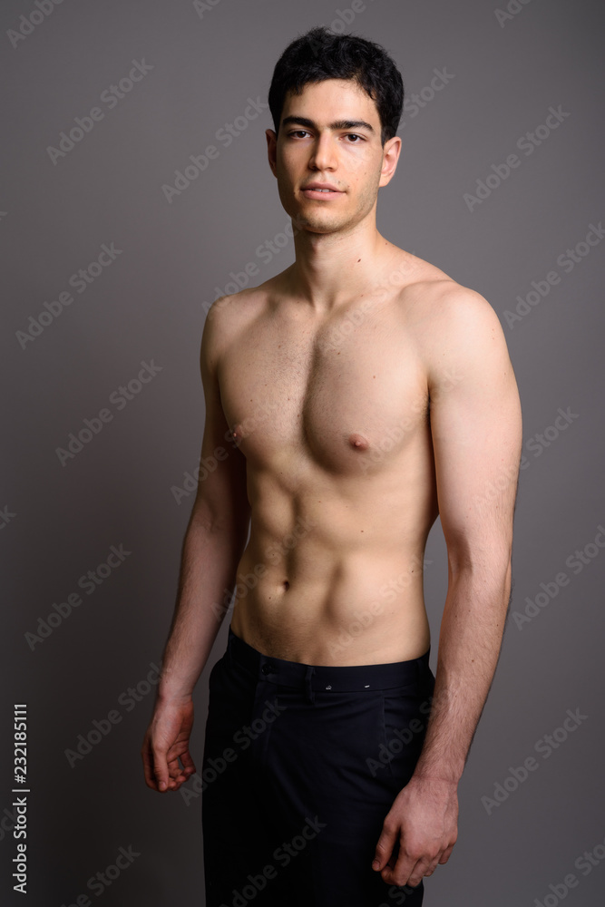 Young handsome man shirtless against gray background