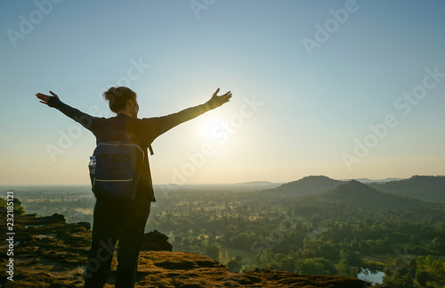 A female traveller standing on the cliff edge with sunrise, embracing nature