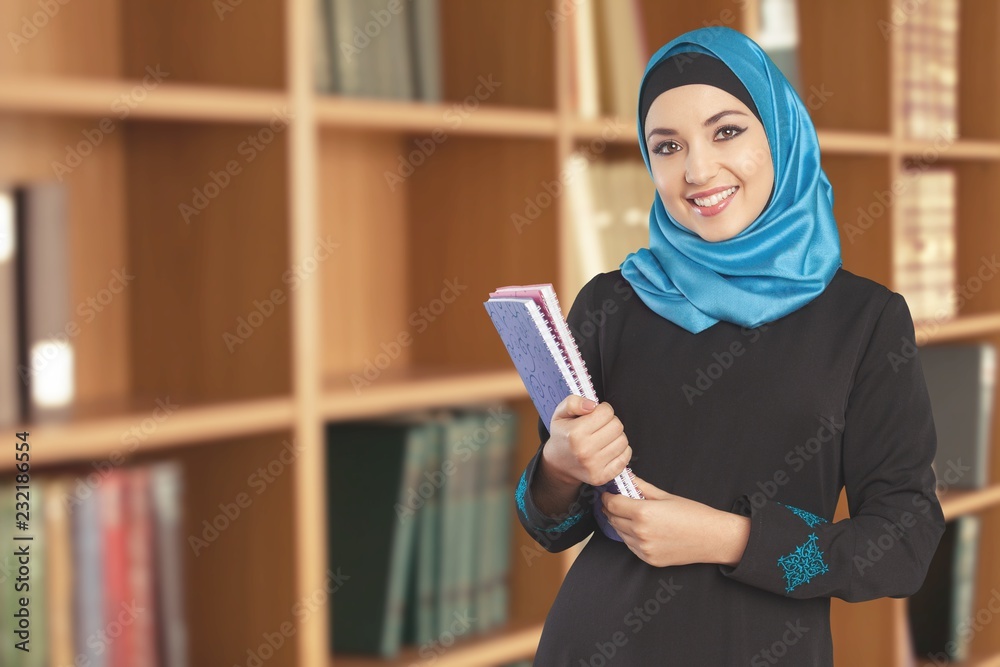 Young woman student holding notebook in library Young woman student holding notebook in library