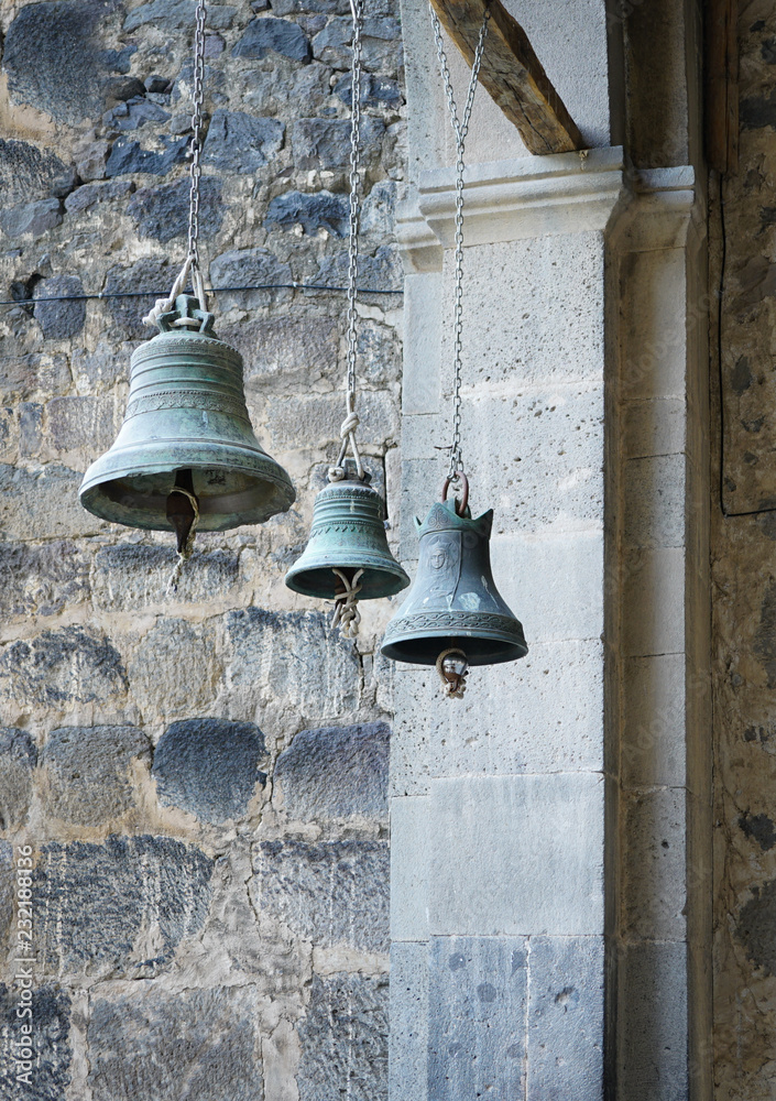 Fototapeta premium three church bells of small, medium and large size hanging in chains