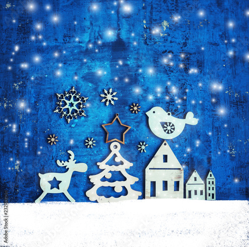 christmas and new year card with tree decorations/wooden figures of houses,snowflakes on the blue rustic background