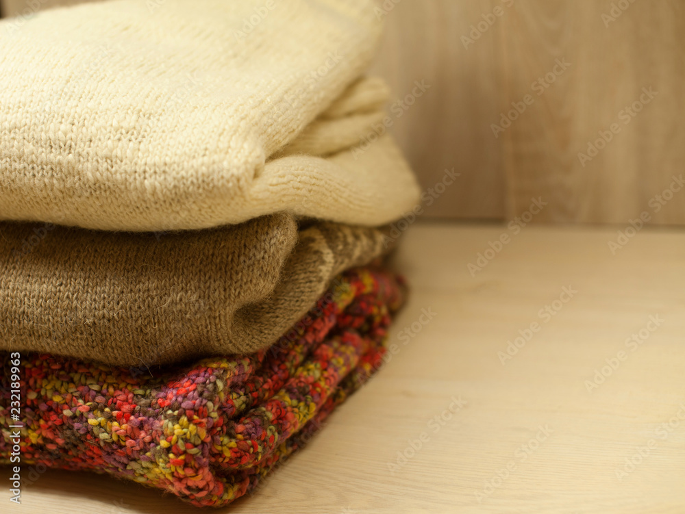 Knitting colorful clothes on wooden background. Winter sweater. Autumn leaves. Handmade
