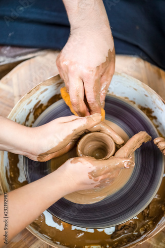 Professions Ideas. Closeup of Hands of  Experienced Male Potter Working with Female Apprentice. Working with Clay Lump on Potter's Wheel in Workshop.