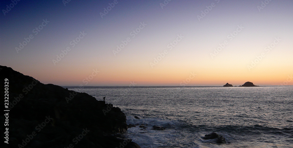 fisherman on rocks at sunset