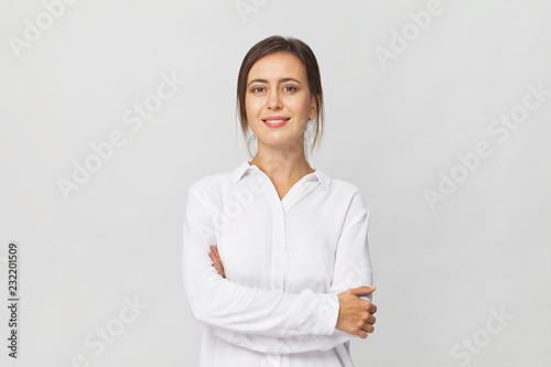 Young confident brunette woman in white elegant shirt smiling portrait against white background