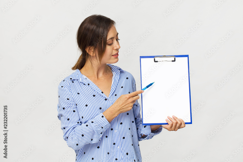 Happy brunette woman in elegant blue shirt showing blank clipboard, isolated on white Happy brunette woman in elegant blue shirt showing blank clipboard, isolated on white