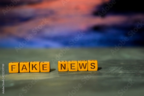 Fake news on wooden blocks. Cross processed image with bokeh background