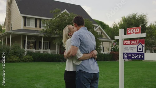 Rear view of proud couple hugging on lawn of sold house for sale / Pleasant Grove, Utah, United States