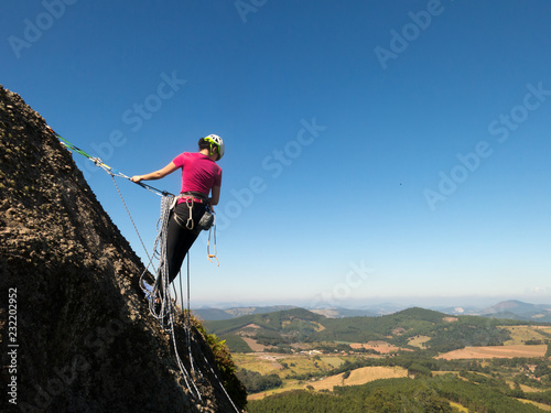 Woman rock climber in a steep rock with beautiful landscape in the background photo