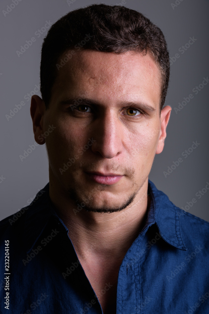 Face of young muscular Persian man against gray background Face of young muscular Persian man against gray background