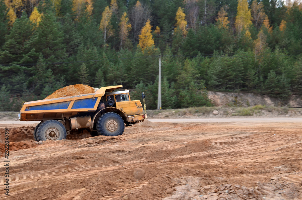 Earth mover loading dumper truck with sand in quarry. Excavator loading sand into dumper truck.Quarry for the extraction of minerals. Large quarry dump truck. Production useful minerals. Earth mover loading dumper truck with sand in quarry. Excavator loading sand into dumper truck.Quarry for the extraction of minerals. Large quarry dump truck. Production useful minerals.