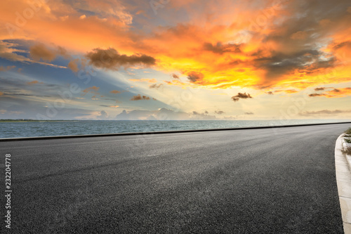 Asphalt road and dramatic sky with coastline at sunset © ABCDstock
