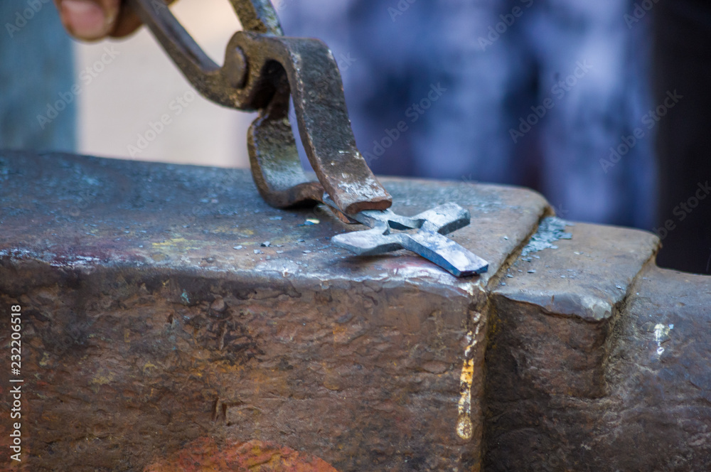 blacksmith performs the forging of hot glowing metal on the anvil