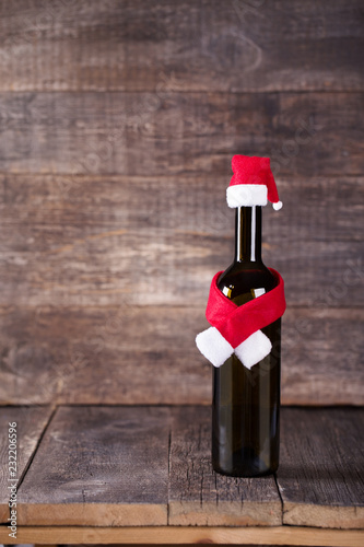 Wine bottle decarated with santa claus hat and scarf on wooden background photo