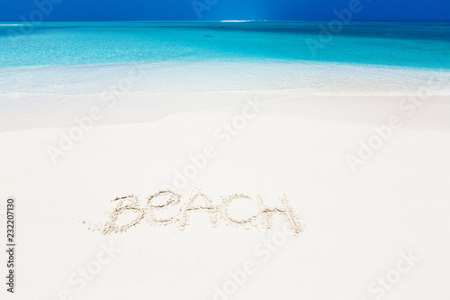 Inscription word BEACH on perfect tropical sandy beach