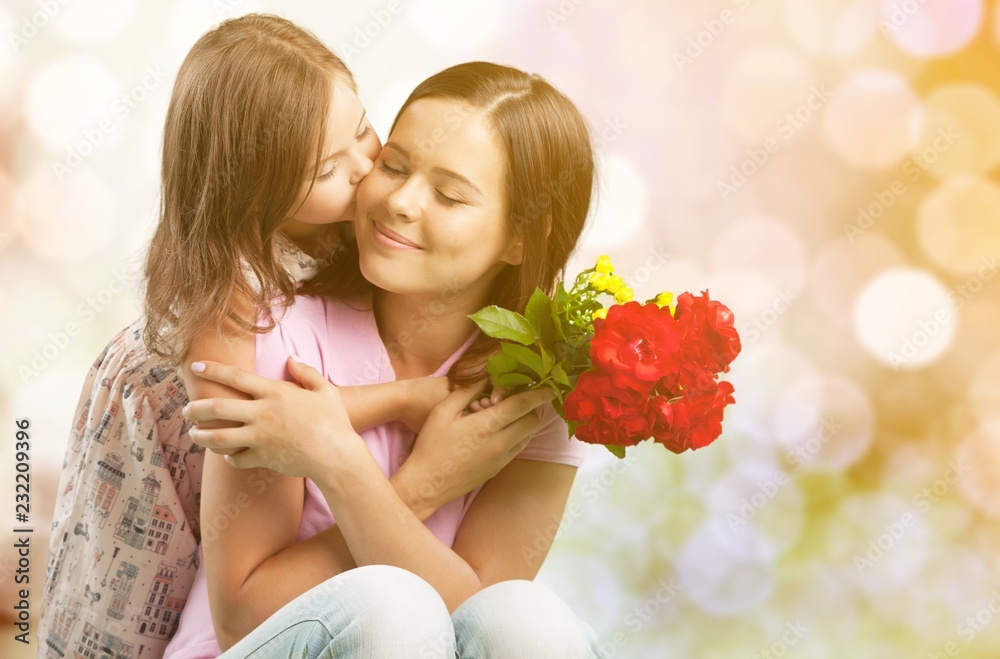 Fototapeta premium Portrait of happy mother and daughter holding flowers