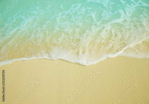 Sea wave on the sunny sandy beach.