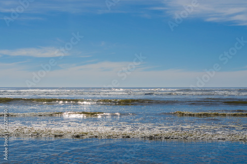 Ocean beach scene  sparkling waves splashing onto seaside shoreline. Scenic travel destination location of beautiful Pacific Northwest coast.