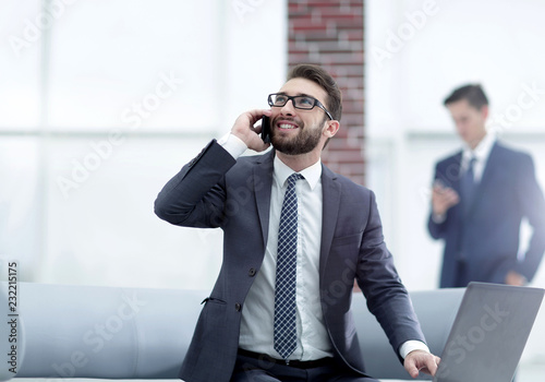 Confident young man talking on phone in office