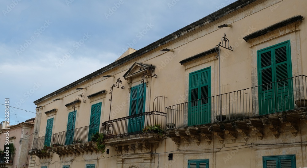 City of Noto. Province of Syracuse, Sicily. Perspective of a house with balconies and all its windows painted of green.