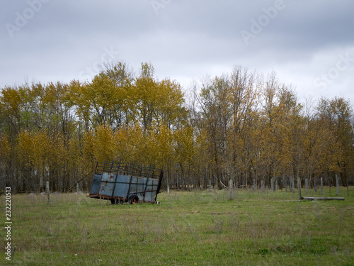 Abandoned Dilapidated Farm Trailer with clouds and autumn trees in northern Minnesota on dreary day