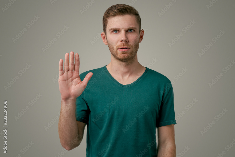 Portrait of a serious man holding hands in a stop sign, warning and preventing you from doing something wrong by looking at the camera with a worried expression. A man shows stop sign with palm Portrait of a serious man holding hands in a stop sign, warning and preventing you from doing something wrong by looking at the camera with a worried expression. A man shows stop sign with palm
