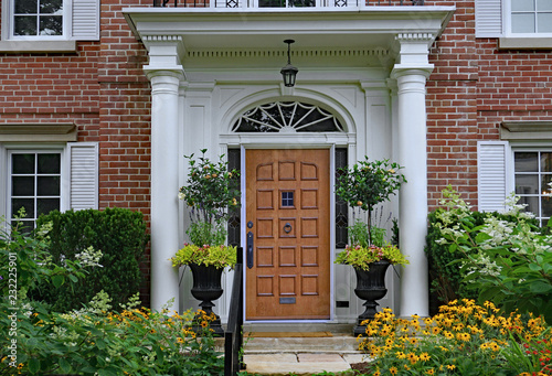 wooden front door of home with elegant portico entrance and  flowers photo