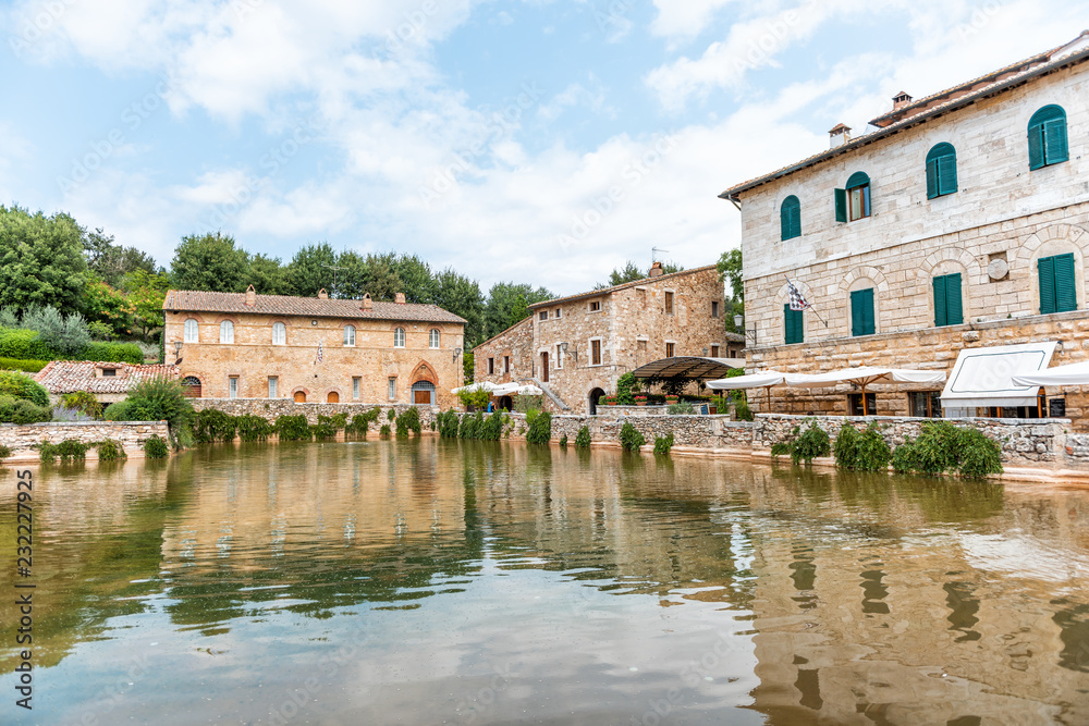 Medieval town of Bagno Vignoni, San Quirico d'Orcia, Val d'Orcia, Tuscany, Italy with hot springs ruins, historical buildings, water pool reflection
