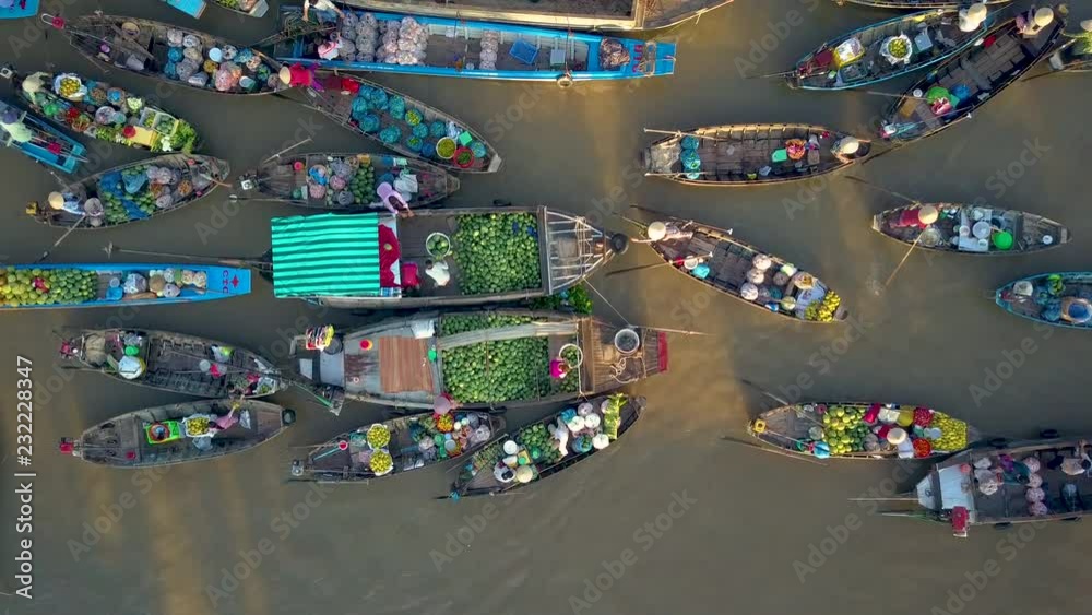 DRONE, TOP DOWN: Flying above local people doing business on the colorful floating market set on the calm murky river in the scenic Vietnamese countryside. People doing business on their wooden boats.