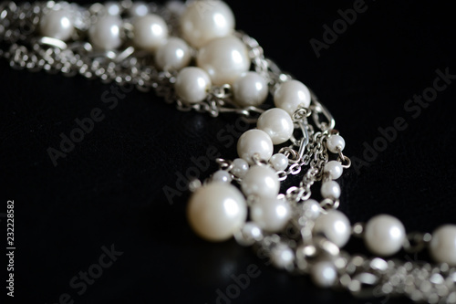 Necklace of white beads and metal chain on a dark background close up