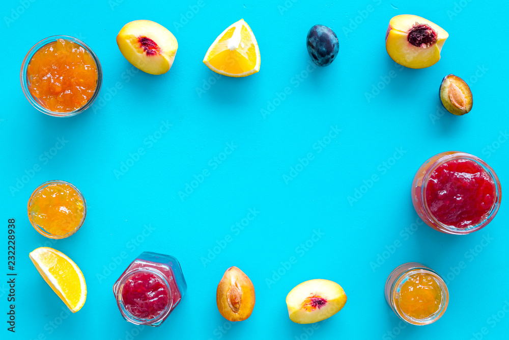 Jams different tastes made of fruits and berries near pieces of fruits on blue background top view frame Jams different tastes made of fruits and berries near pieces of fruits on blue background top view frame