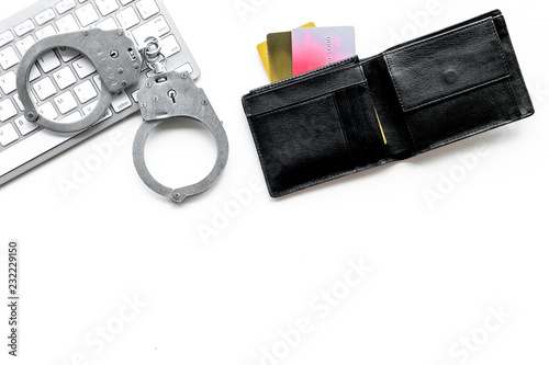 Arrest for stealing money online concept. Handcuff near keyboard and bank card on white background top view copy space