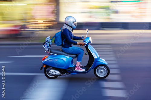 Murais de parede young woman with a scooter on the move in the city