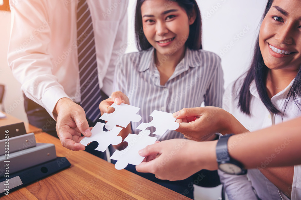 Image of a group of business people using a jigsaw puzzle to demonstrate the need to work in the same direction to work fully and effectively. Image of a group of business people using a jigsaw puzzle to demonstrate the need to work in the same direction to work fully and effectively.