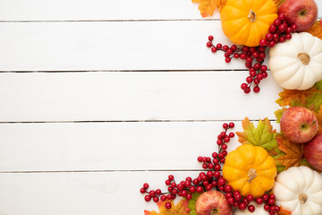 Top view of  Autumn maple leaves with Pumpkin and red berries on white wooden background. Thanksgiving day concept.