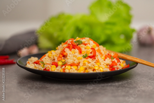 Chinese fried rice with vegetables, served on a plate with chopsticks. Selective focus