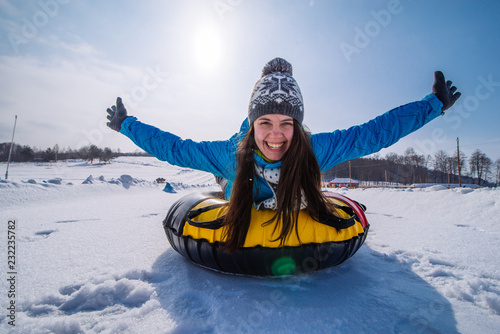 young pretty woman at snow tubing rise hands up. slide from snow hill