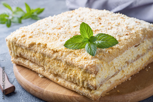 Layered cake with cream Napoleon millefeuille vanilla slice with mint on dark background. photo